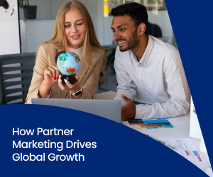 Two coworkers sit at a laptop, the woman holds a small globe in her hand as they discuss partner marketing and global growth